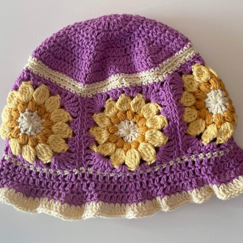 Close up of mauve crochet sunflower bucket hat with cream edging and sunflowers around the middle of the hat.
