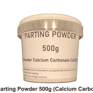 May include: A white plastic container labeled "PARTING POWDER" with the text "500g" and "(Powder Calcium Carbonate CaCO3)". The container has a clear lid and is used for various crafting and industrial applications.