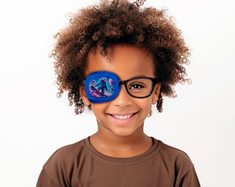 May include: A child wearing a blue eye patch with a cartoon character design. The eye patch is over the child's left eye. The child is also wearing black framed glasses and a brown shirt.