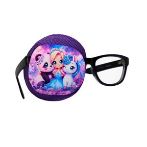 Könnte beinhalten: Ein lila Augenklappe mit einem farbenfrohen Aufdruck eines Pandas, eines Mädchens und eines Einhorns. Die Augenklappe ist an einer schwarzen Brille befestigt.