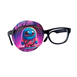 May include: A purple and pink eye patch with a cartoon astronaut wearing a red spacesuit and a blue fuzzy head. The eye patch is attached to a pair of black framed glasses.
