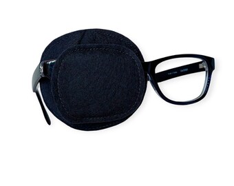 May include: Black eye patch with a soft, black felt covering. The patch is attached to a pair of black framed glasses with clear lenses. The glasses have the text "CA 2300" printed on the right temple.