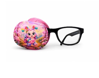 May include: A pink eye patch with a colorful cartoon bunny design, paired with black-framed eyeglasses. The eye patch features a vibrant illustration of a bunny with a heart, set against a floral background.