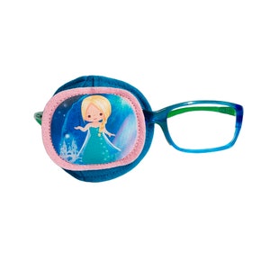 Può includere: Cerotto per l'occhio blu con bordo rosa e un'immagine stampata di una principessa con un vestito blu e un castello. Il cerotto è attaccato a un paio di occhiali blu e verdi.