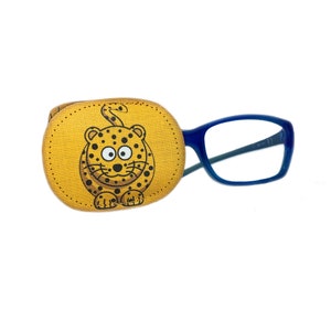 May include: A yellow eye patch with a cartoon leopard design. The eye patch is attached to a pair of blue framed glasses.