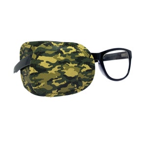 May include: A camouflage eye patch with a black frame attached to a clear lens eyeglass.