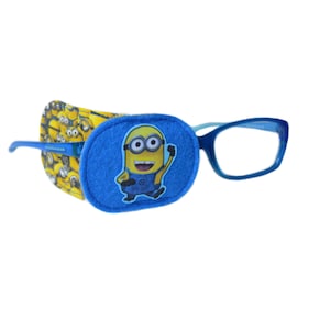 May include: Blue eyeglasses with a Minion-themed eye patch. The eye patch is blue with a Minion character graphic. The glasses have blue frames and are designed for children. The eye patch is attached to the glasses.