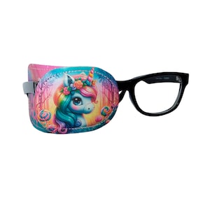 May include: A colorful unicorn eye patch with a rainbow mane and a pink flower crown. The patch is attached to a black plastic frame.