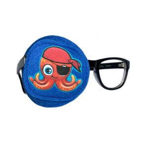 Può includere: Parche per l'occhio in feltro blu con un polpo che indossa un cappello da pirata rosso e un paraluce. Il paraluce è attaccato a degli occhiali di plastica neri.