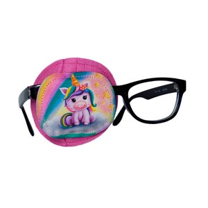 May include: Pink eye patch with a unicorn design. The patch has a rainbow background with stars and a unicorn sitting on a cloud. The patch is attached to a pair of black framed glasses.