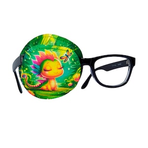 May include: A green eye patch with a cartoon dragon and a dragonfly design. The eye patch is attached to a pair of black framed glasses.
