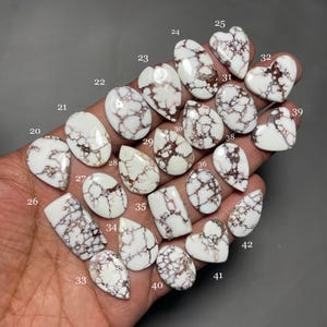 May include: A collection of 22 white and brown, natural, cabochon, gemstone,  cabochons. The cabochons are various shapes and sizes, including teardrop, oval, and heart shapes. The cabochons are numbered 20 through 42.