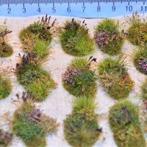 Puede incluir: Un conjunto de 16 mechones de hierba en miniatura de color verde, marr&oacute;n y morado con acentos coloridos. Los mechones est&aacute;n dispuestos en un patr&oacute;n de cuadr&iacute;cula sobre una superficie blanca.