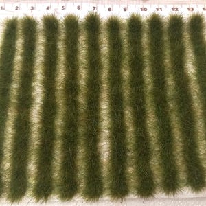 May include: A sheet of green static grass tufts, arranged in rows, for model railroading or miniature landscaping.