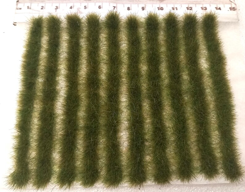 May include: A sheet of green static grass tufts, arranged in rows, for model railroading or miniature landscaping.