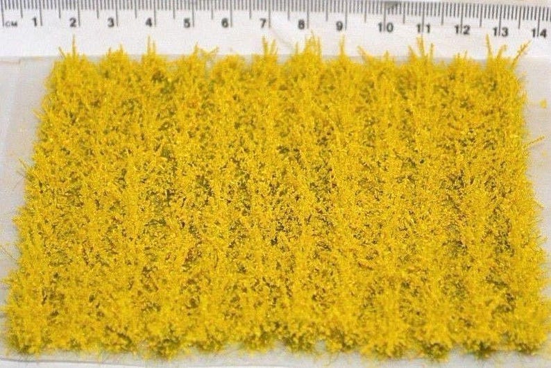 May include: A sheet of yellow static grass for model railroading or miniature gaming. The grass is approximately 14 inches long and is shown next to a ruler.