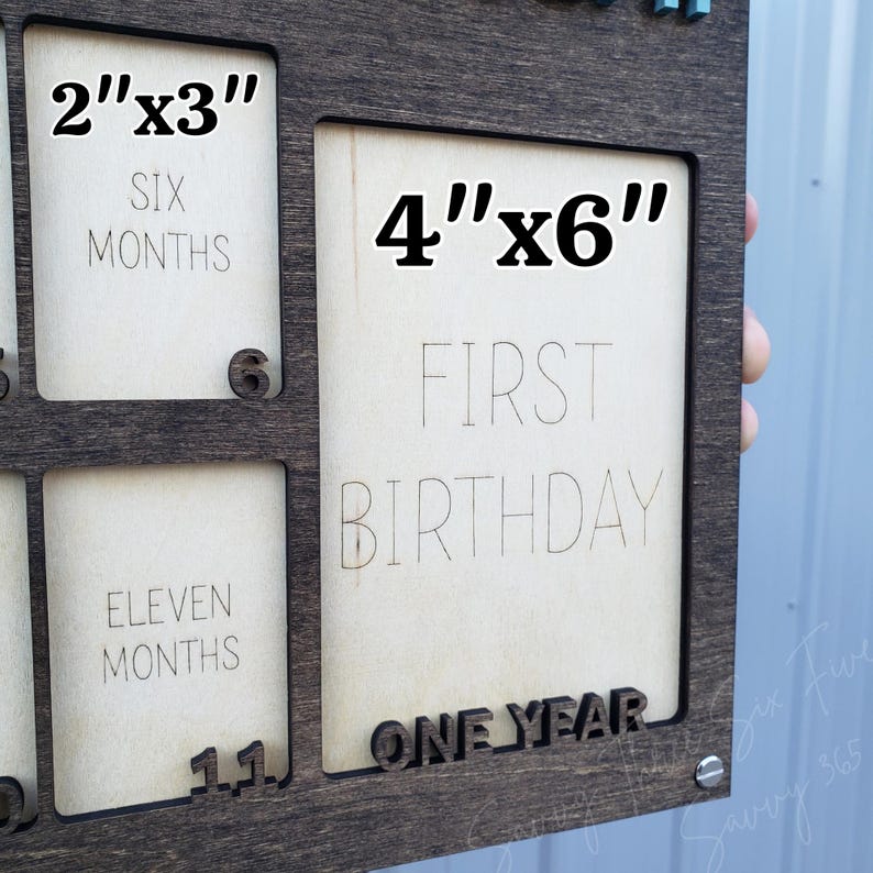 May include: A wooden photo frame with spaces for multiple photos. The frame has openings for 2"x3" and 4"x6" photos. Text includes "SIX MONTHS", "ELEVEN MONTHS", "FIRST BIRTHDAY", and "ONE YEAR". The frame is dark brown.