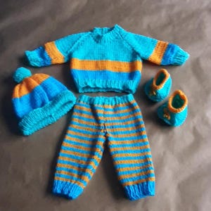 Handgestrickte Puppenkleidung, Hosen, Pullover und Mützen.