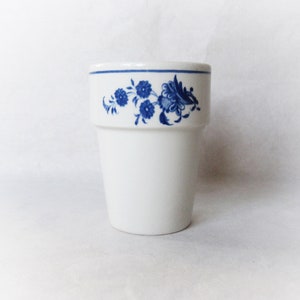 May include: A white ceramic cup with a blue floral design around the top.