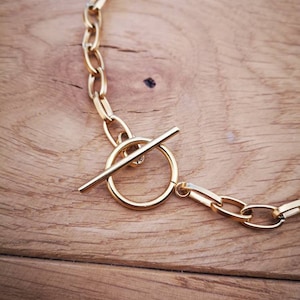 Puede incluir: Un collar de cadena dorada con cierre de palanca. La cadena est&aacute; hecha de eslabones gruesos de forma ovalada.