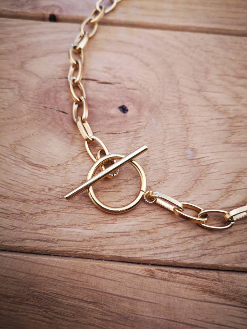 Puede incluir: Un collar de cadena dorada con cierre de palanca. La cadena est&aacute; hecha de eslabones gruesos de forma ovalada.