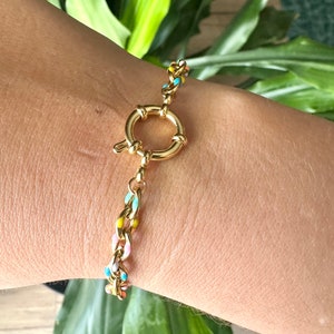 May include: A gold chain bracelet with colorful enamel accents. The bracelet has a toggle clasp.