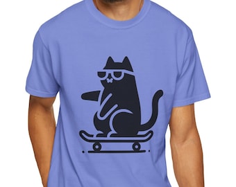 May include: A light blue t-shirt featuring a black graphic of a cat wearing sunglasses and skateboarding. The cat is sitting on the skateboard with its front paw extended.