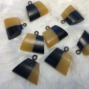 May include: Seven black and yellow pendant charms with a unique design. Each charm has a black top and a yellow bottom.
