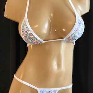May include: White and iridescent bikini set. The top is a triangle style with thin straps, and the bottoms are a thong style. The fabric has a shimmering, textured pattern. The bikini is displayed on a mannequin.