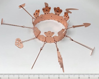 Peut inclure: Une couronne en cuivre avec sept breloques pendantes, dont une clé, un éclair et une lance. La couronne mesure environ 15 cm de diamètre.