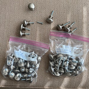 May include: Two bags of silver cabinet knobs with screws. One bag labeled "20 Small Screws for Cabinets" and the other labeled "20 Long Screws for Drawers".