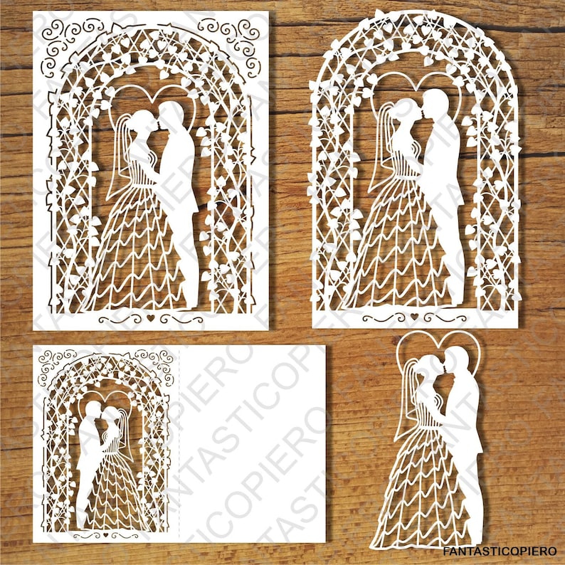 May include: White paper cut-out design of a wedding arch with a couple standing under it. The arch is decorated with hearts and vines. The couple are holding hands and looking at each other.