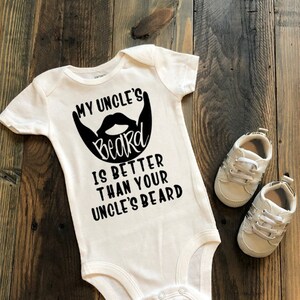 May include: White baby onesie with black text that reads "My Uncle's beard is better than your Uncle's beard". A black and white illustration of a beard is above the text.
