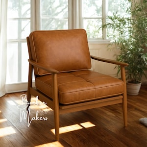 May include: A mid-century modern armchair with a brown leather cushion and backrest. The chair has a wooden frame and armrests. The seat cushion has a tufted design. The chair is in a well-lit room with a window and plants.