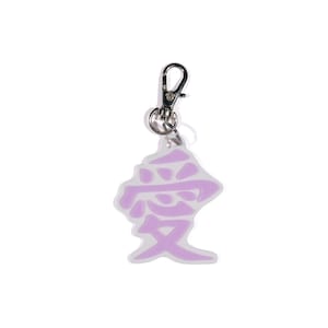 May include: A lavender-colored keychain with a silver clasp. The keychain features a Japanese character design. The character is in a light purple color and is set against a white background.
