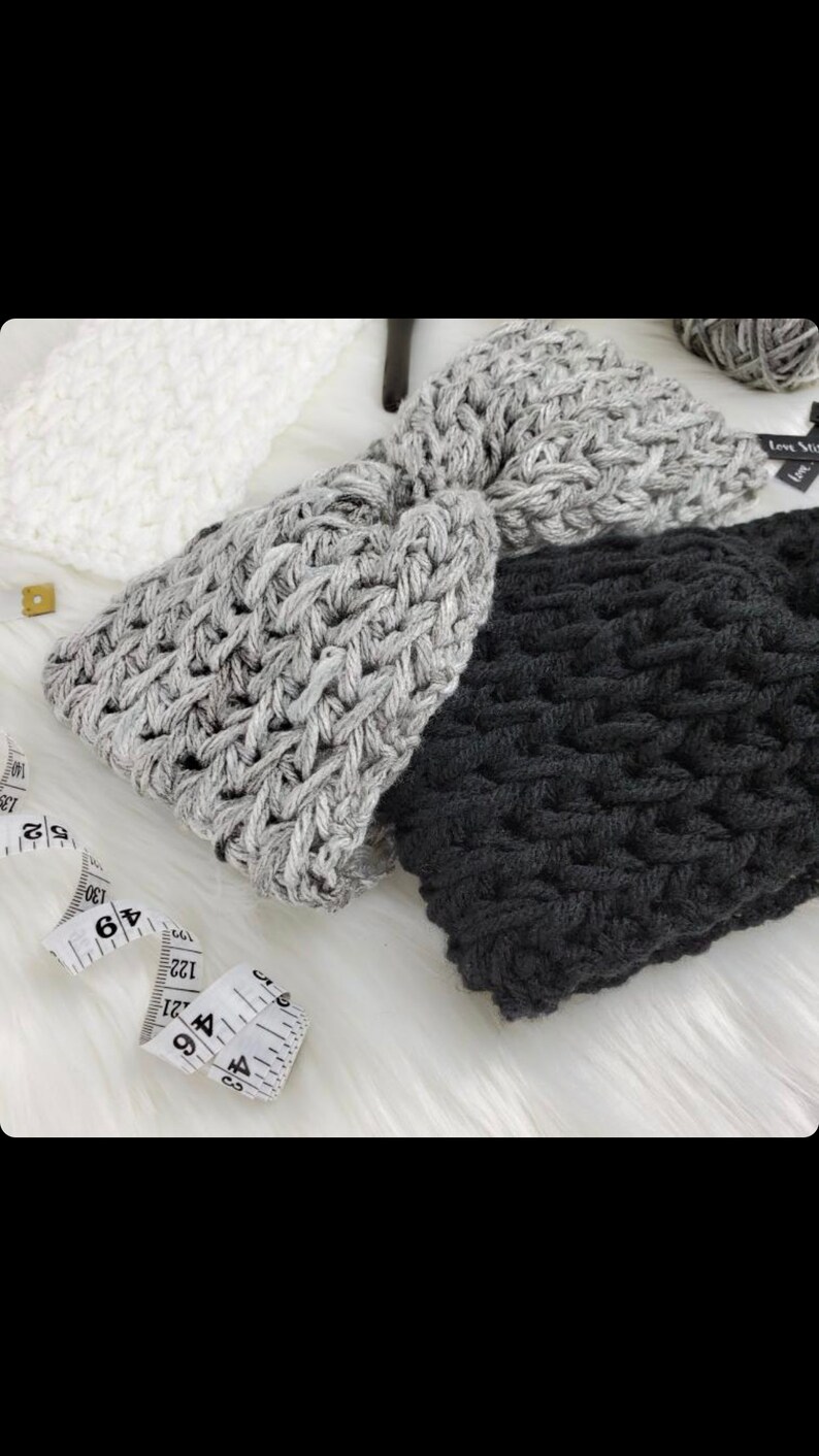 May include: Three crocheted headbands in gray, black, and white. The headbands are made with a chunky yarn and have a simple, textured design.