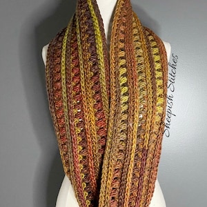 May include: A crocheted infinity scarf in shades of brown, orange, and yellow. The scarf is made with a textured stitch and has a simple, elegant design.