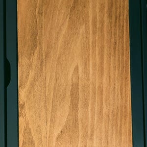 May include: A wooden box with a dark green frame. The box is closed and the wood grain is visible.