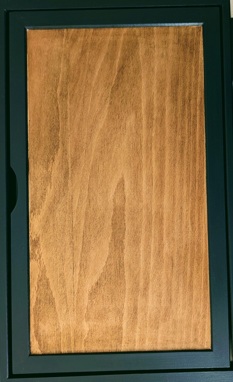 May include: A wooden box with a dark green frame. The box is closed and the wood grain is visible.