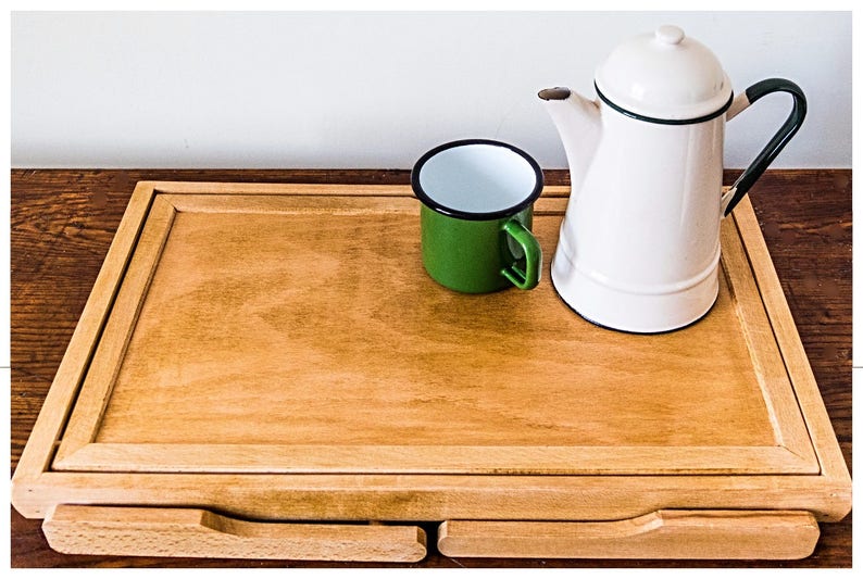 May include: A wooden serving tray with two drawers, a green enamel mug, and a white enamel teapot with a black rim and green handle.