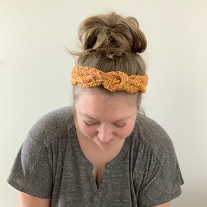 Puede incluir: Una mujer con una diadema anudada con un patr&oacute;n de color marr&oacute;n y naranja.