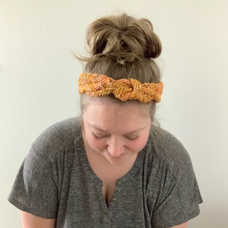 Puede incluir: Una mujer con una diadema anudada con un patr&oacute;n de color marr&oacute;n y naranja.