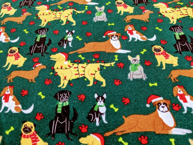May include: A green fabric featuring a repeating pattern of various dog breeds. Some dogs wear Santa hats, scarves, or are decorated with Christmas lights. The design includes paw prints and bones, creating a festive holiday theme.
