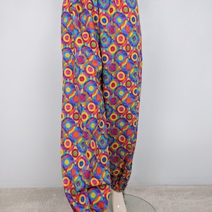 May include: Colorful pants with a geometric pattern of overlapping circles in shades of pink, yellow, blue, green, and orange. The pants have an elastic waistband and cuffed legs.