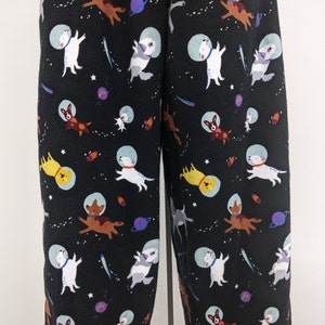 May include: Black pajama pants with a repeating pattern of dogs in spacesuits, stars, and planets.