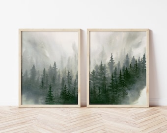 May include: A set of two watercolor paintings depicting a misty forest scene with tall, dark green trees. The paintings are framed in natural wood frames and are perfect for adding a touch of nature to any room.