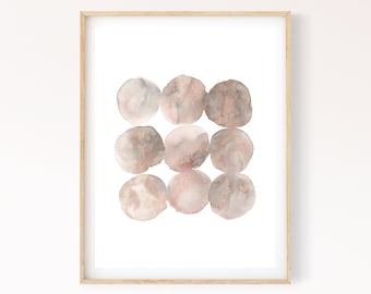 Könnte beinhalten: Ein gerahmter Aquarelldruck mit neun abstrakten Kreisen in Beige-, Braun- und Rosatönen. Das Kunstwerk wird in einem hellen Holzrahmen vor einem weißen Hintergrund präsentiert. Die Signatur des Künstlers ist unten rechts sichtbar.