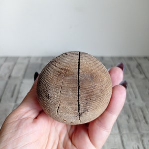 May include: A wooden ball with a crack down the center. The ball is brown and has a rough texture.