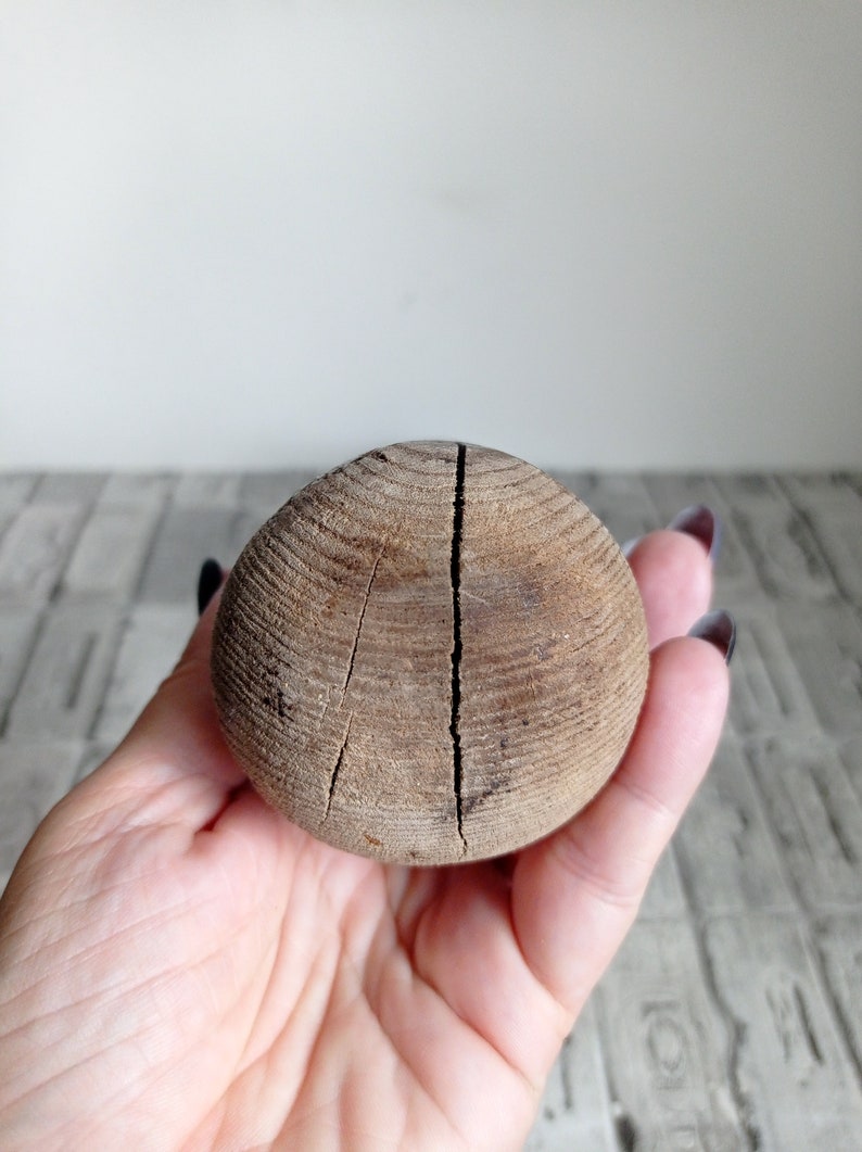 May include: A wooden ball with a crack down the center. The ball is brown and has a rough texture.