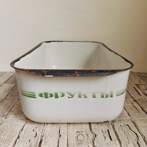 May include: White rectangular enamelware container with a green stripe and the word "FRUCTЫ" in green lettering. The rim is dark brown with signs of wear. The container is likely vintage and suitable for kitchen or storage use.